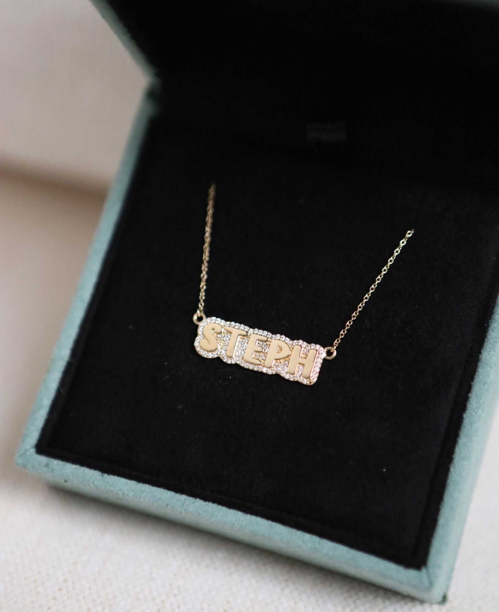 the "STEPH" Polly Custom Diamond Bubble Name Necklace in Yellow Gold placed in a luxurious jewelry box.