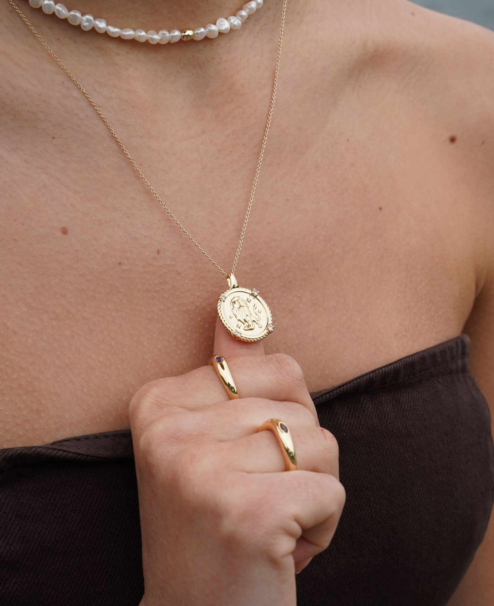 Gold necklace with a pendant worn by a person, with a close-up on the jewelry.