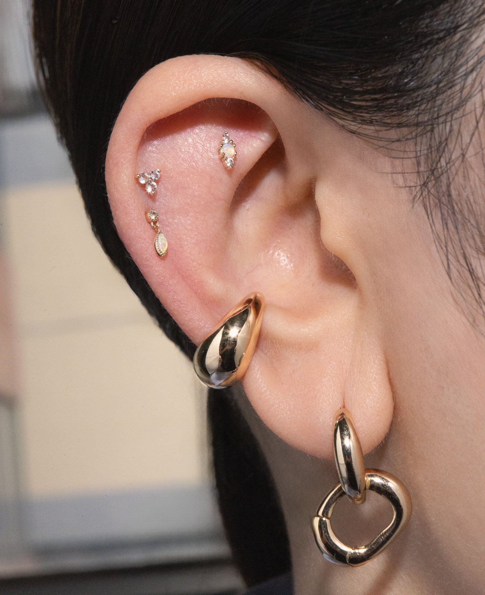 Model shot of Odette Opal Two-stone Flatback Post, Clover Three-stone White Sapphire Flatback Post, Laurel Opal Dangle Flatback Post, Betsy Chunky Gold Ear Cuff and Hannah Interchangeable Gold Hoop Earrings.