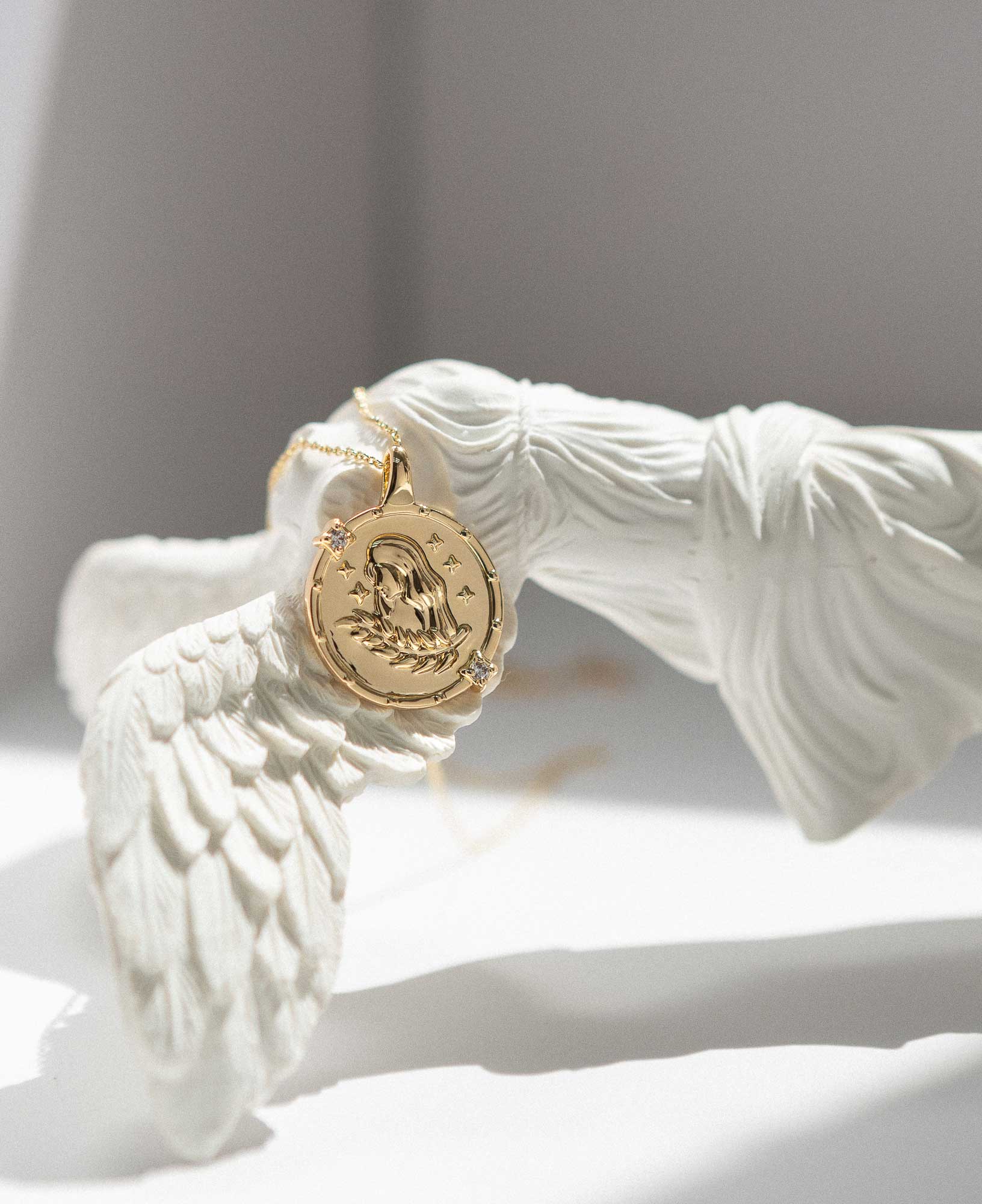 flatlay picture of Virgo Horoscope Gold Pendant Necklace on Greek Goddess Statue.