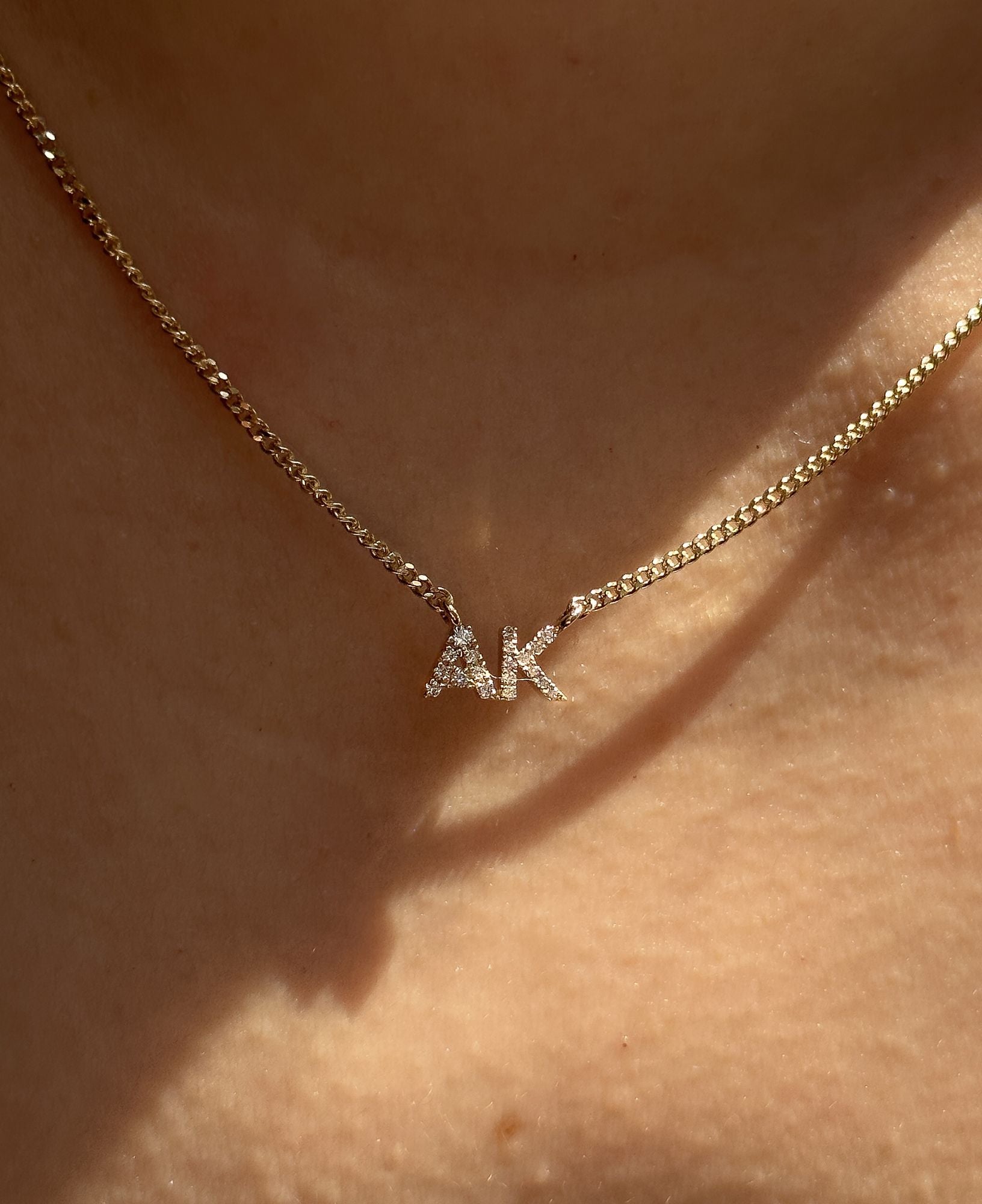 A model wearing the "AK" Lottie Custom Diamond Nameplate Chain Necklace in Yellow Gold.