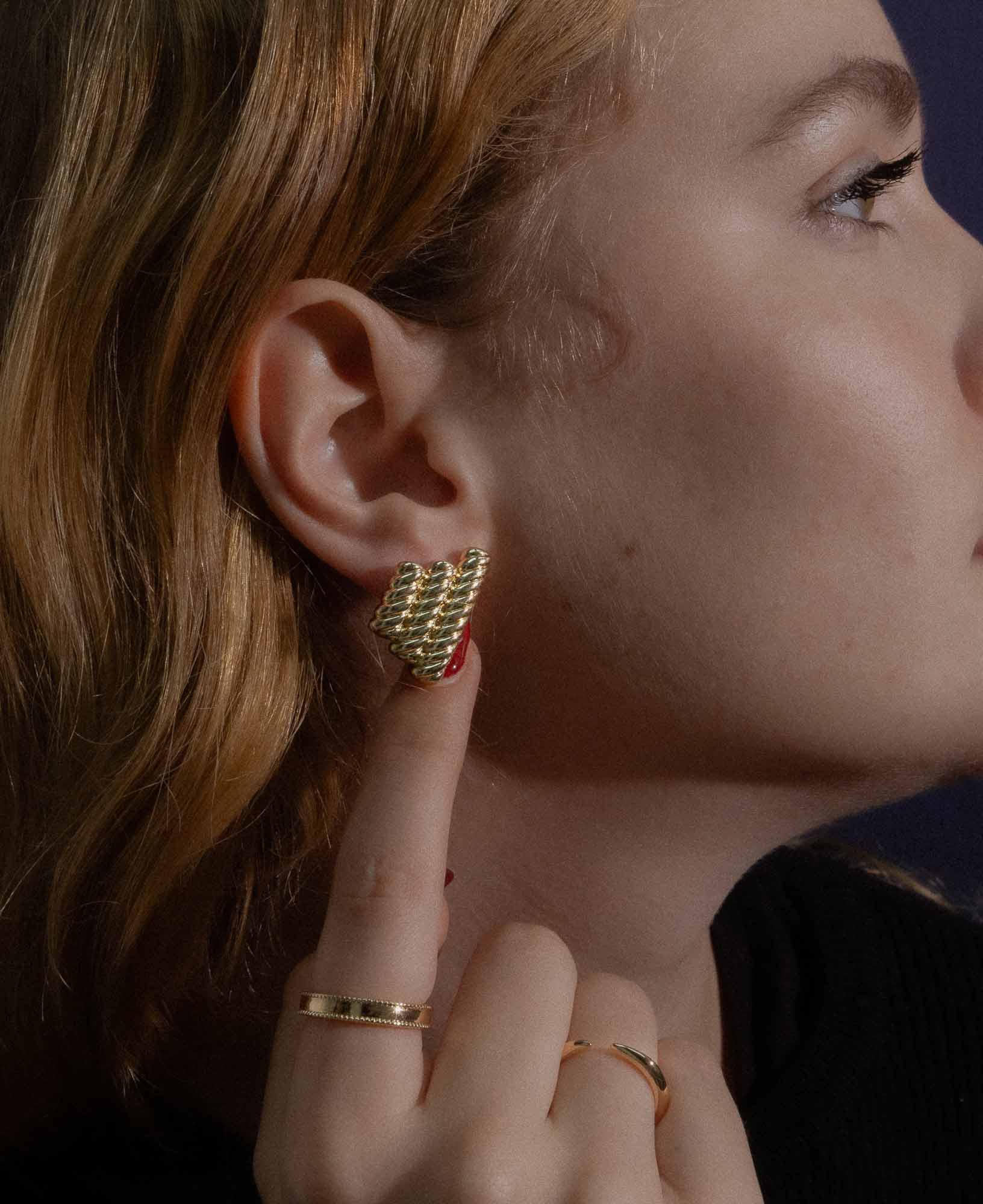 dark and festive close-up shot in the studio featuring the Catherine Rope Link Textured Gold Clip Earrings, Imogen Gold Cuff Open Ring and Gladys Beaded Gold Band Ring.