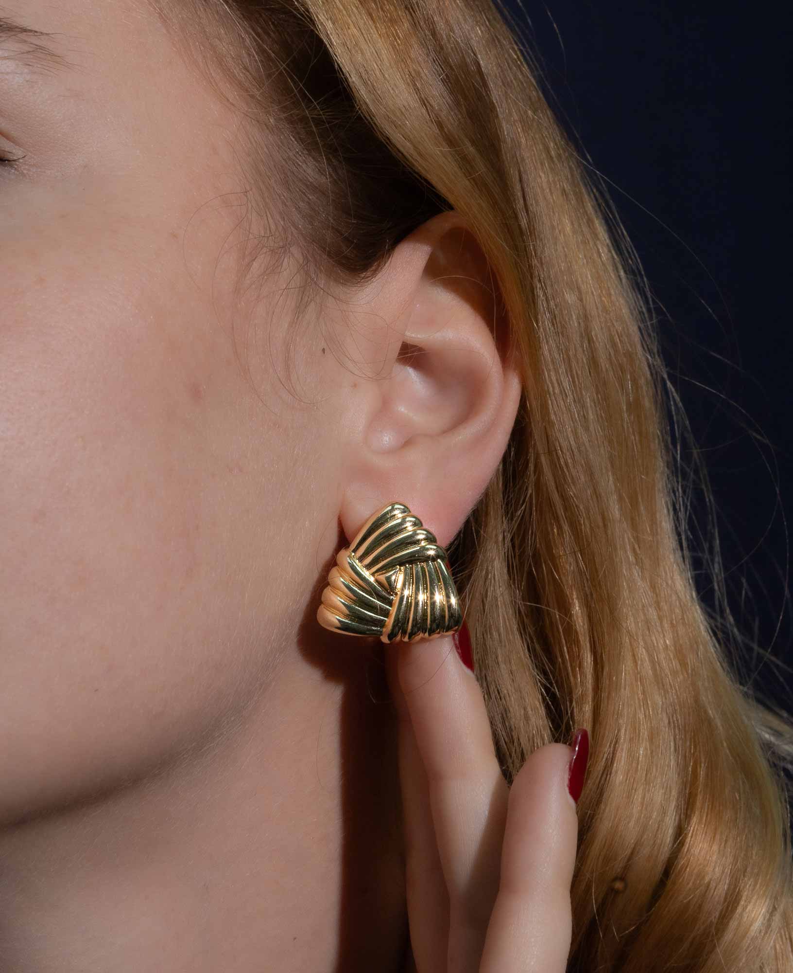 dark and festive close-up shot featuring the Eleanor Triangle Braided Gold Chunky Earrings on a model.