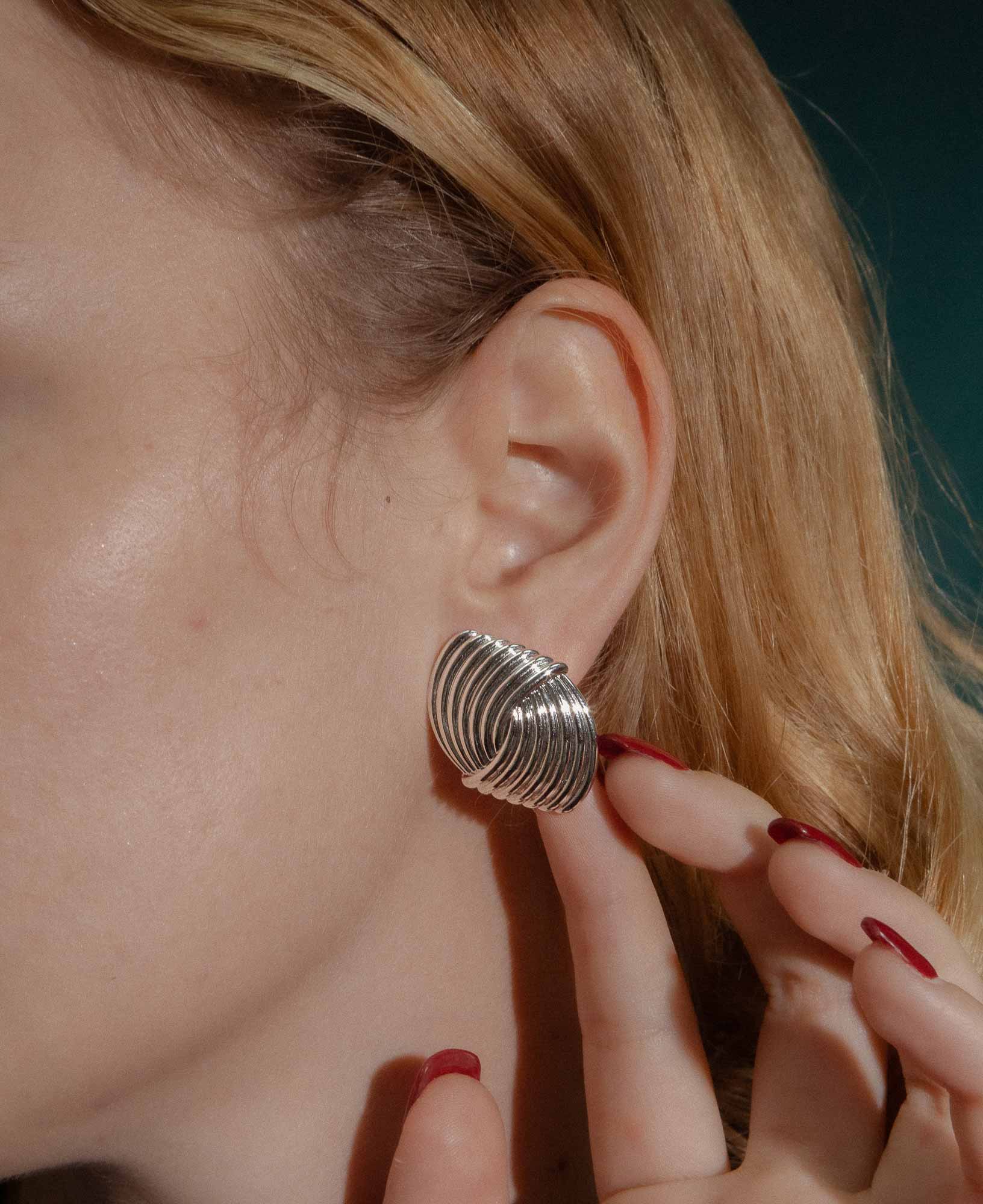 dark and festive close-up shot featuring the Laverne Illusion Knot Silver Statement Earrings.