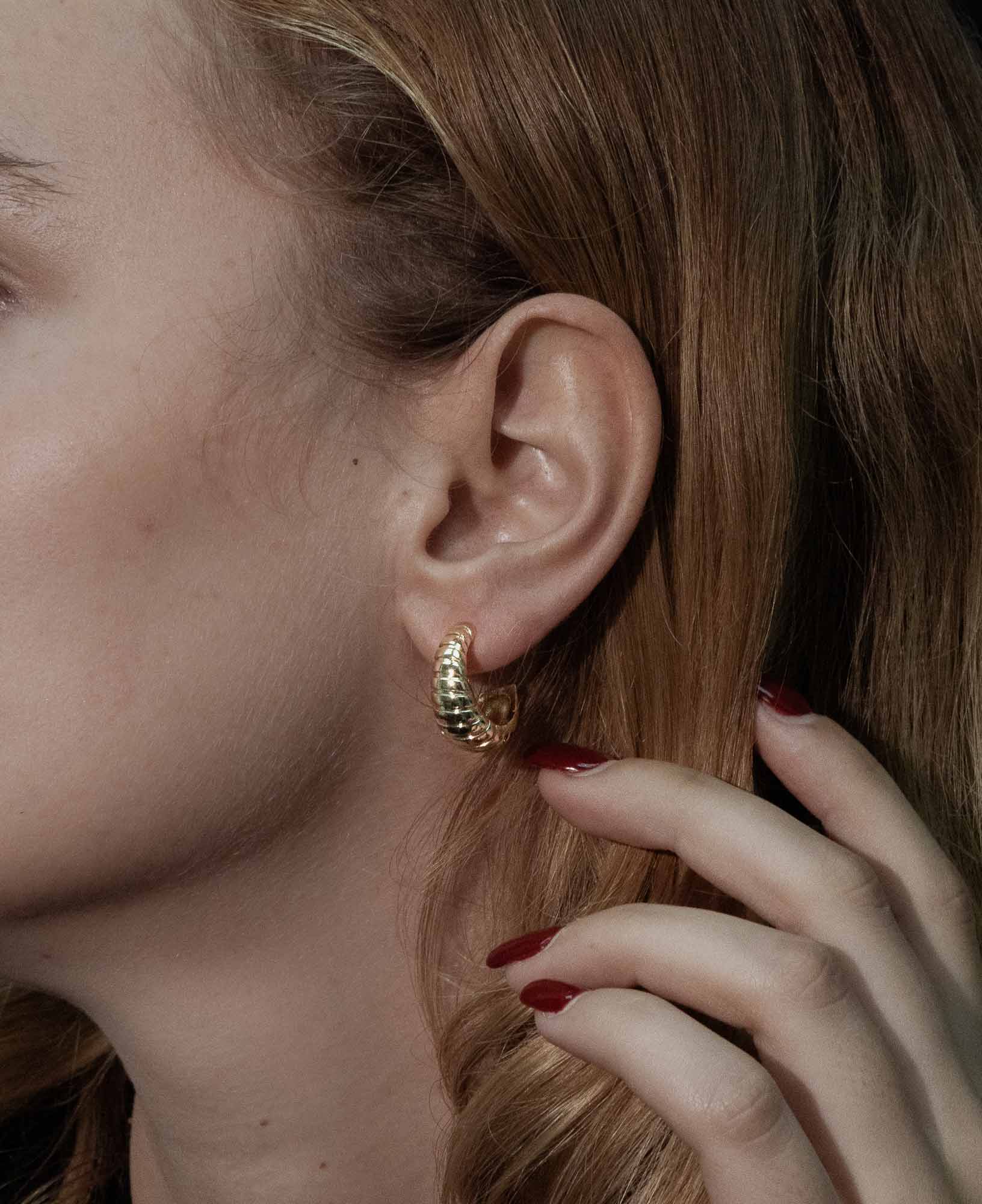 dark and festive close-up shots of the Maeve Croissant Half-Hoop Earrings on a model.