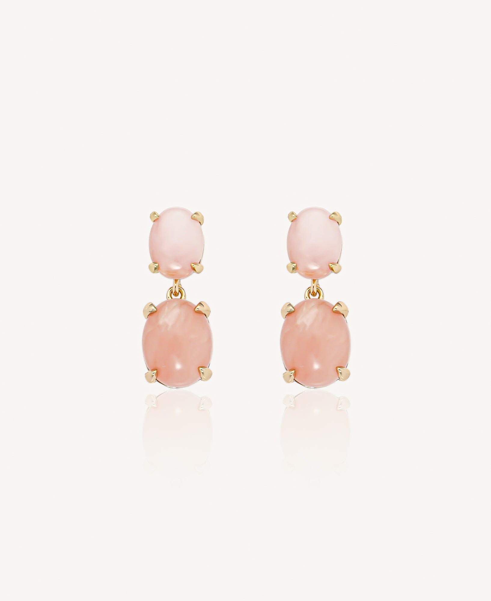 Pair of gold drop earrings with pink opal stones on a plain white background