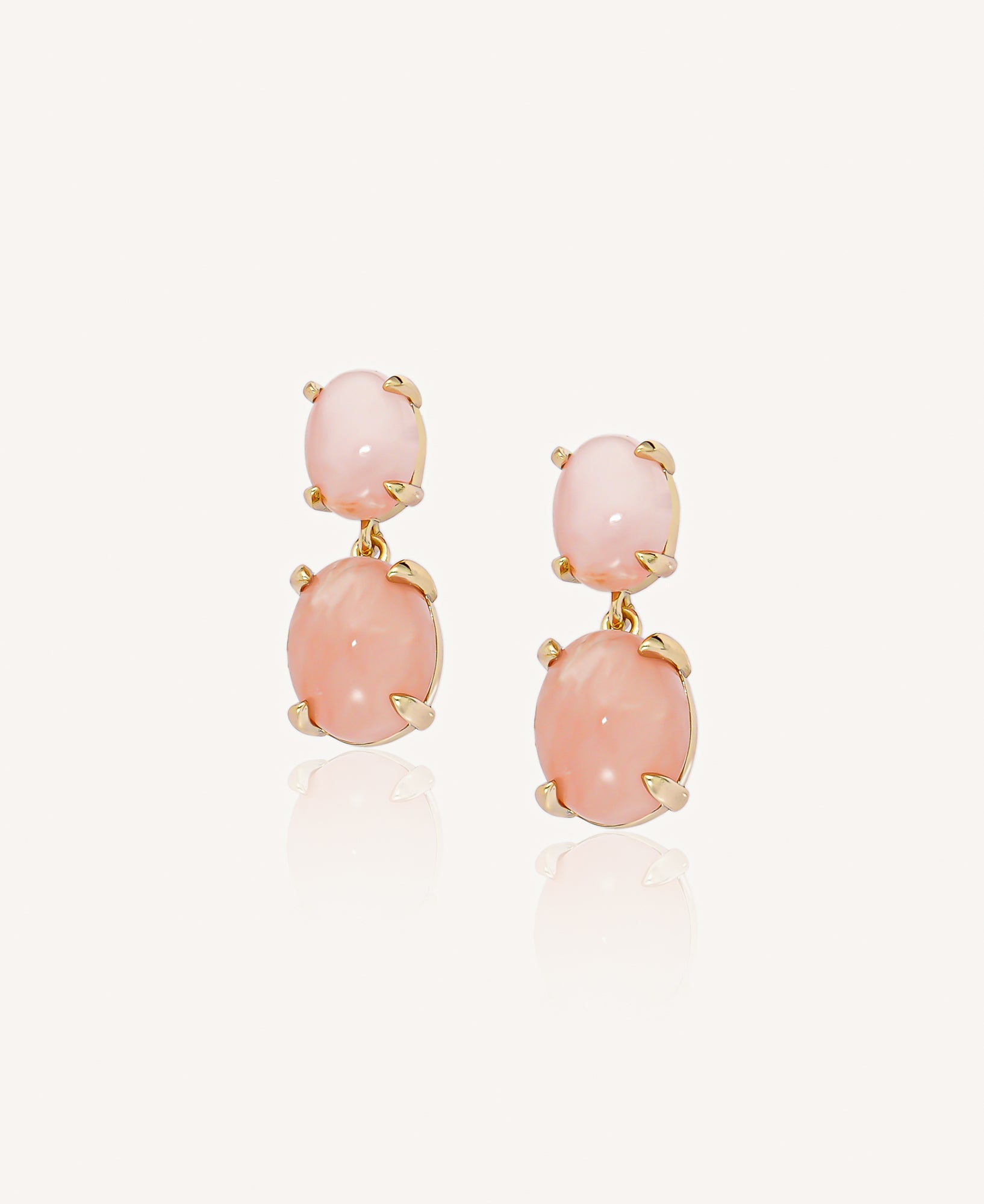 Pair of gold drop earrings with pink opal stones on a plain white background