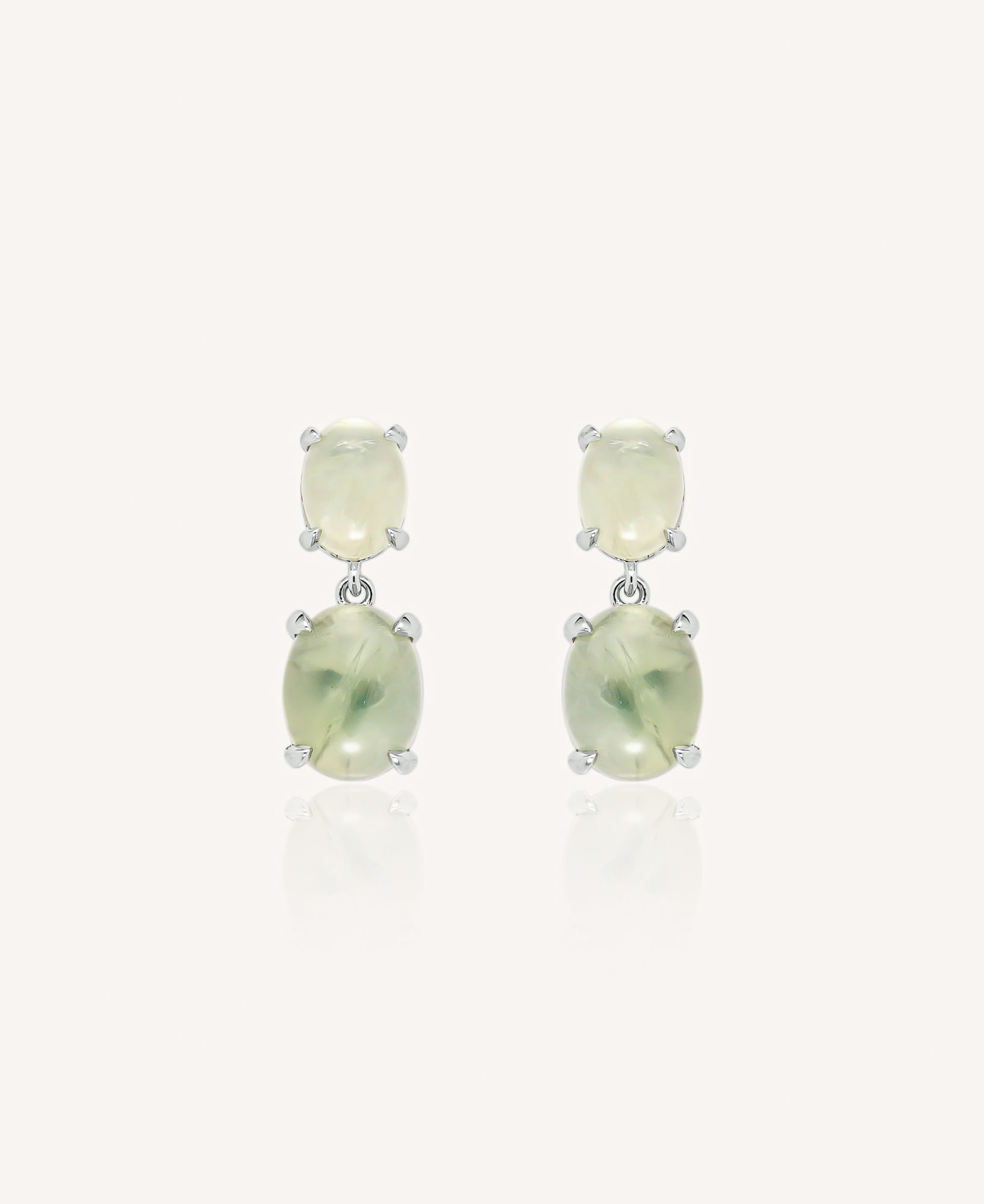 Pair of drop earrings with green gemstones on a white background