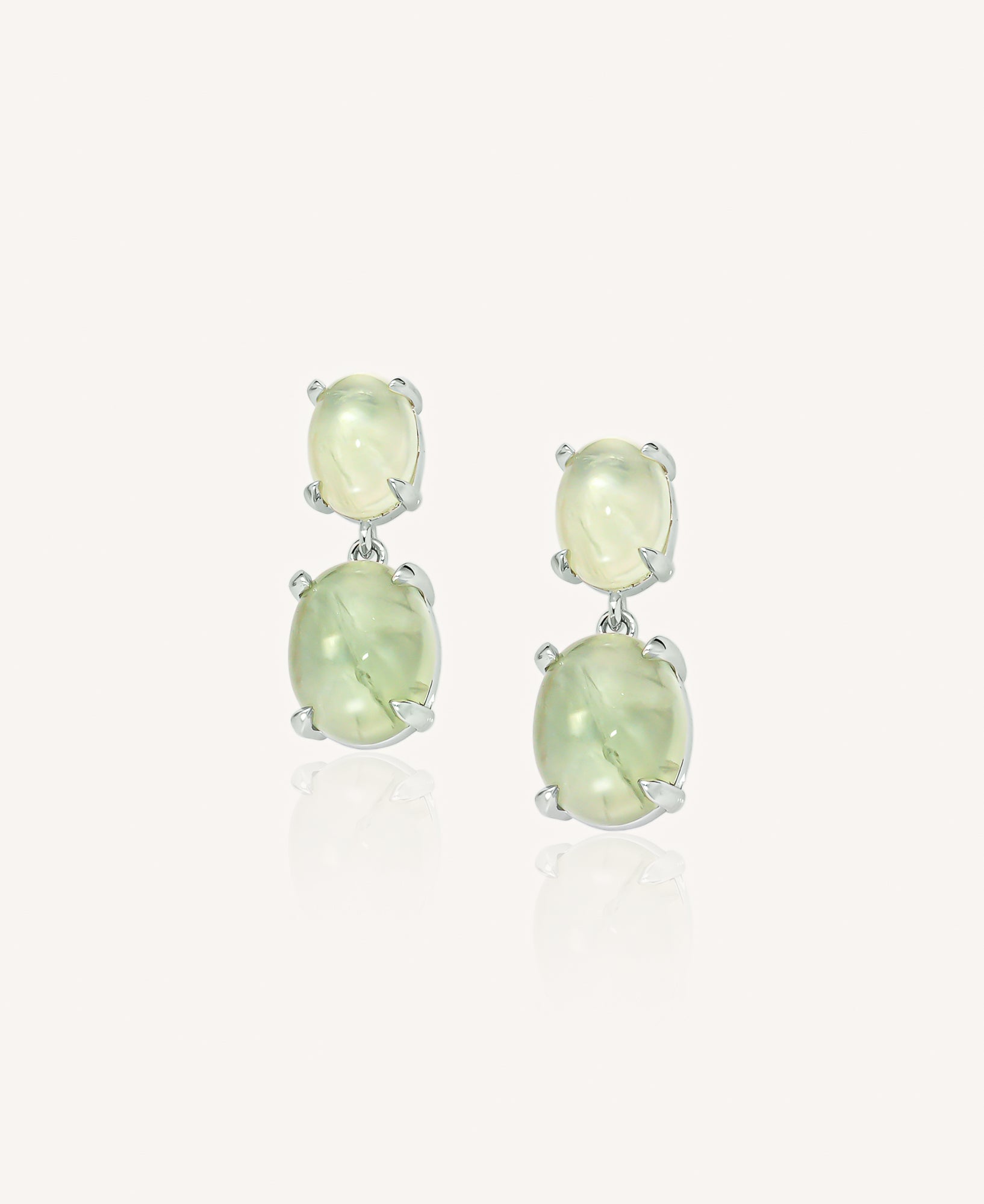 Pair of drop earrings with green gemstones on a white background