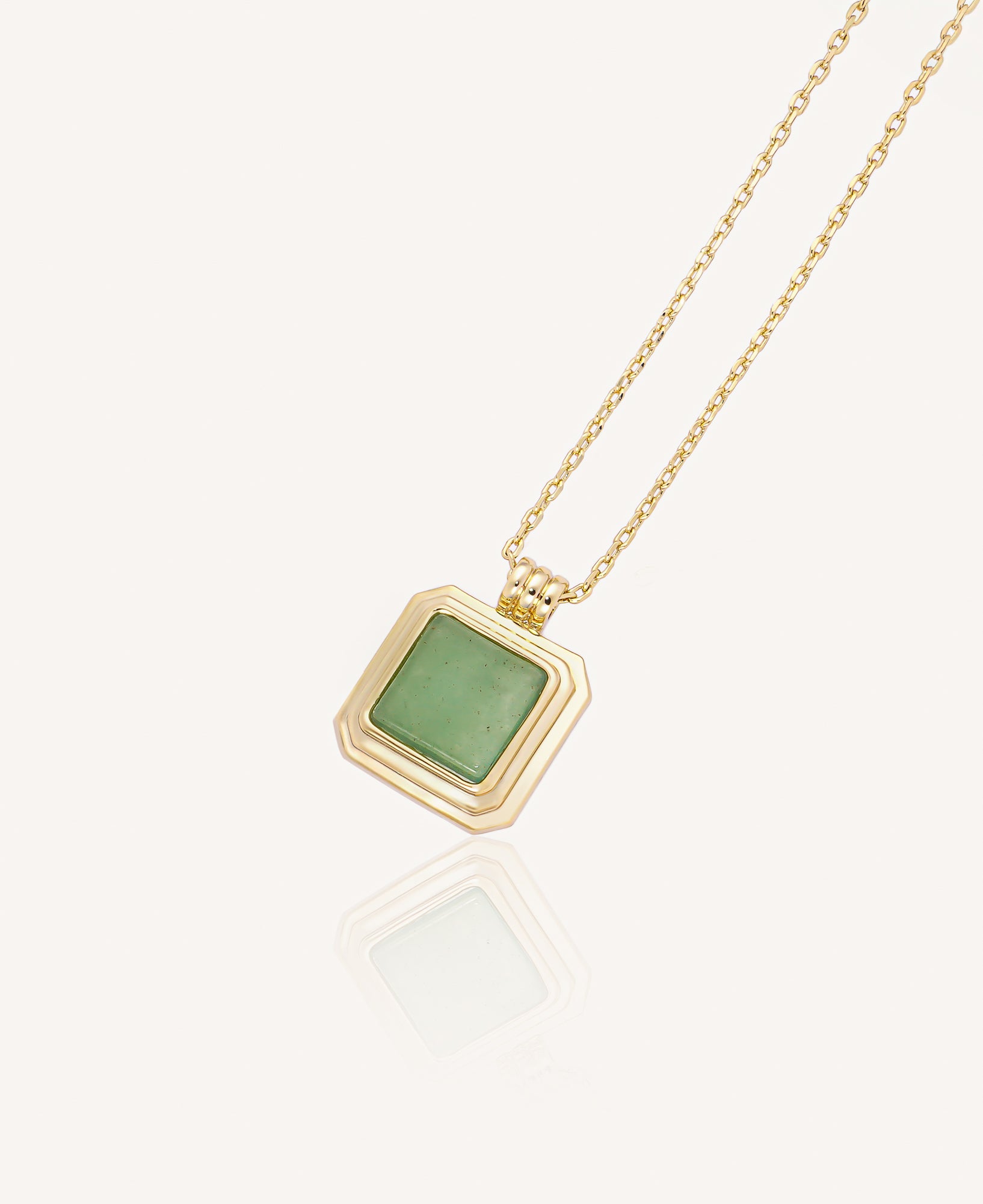 Gold necklace with a green gemstone pendant on a white background