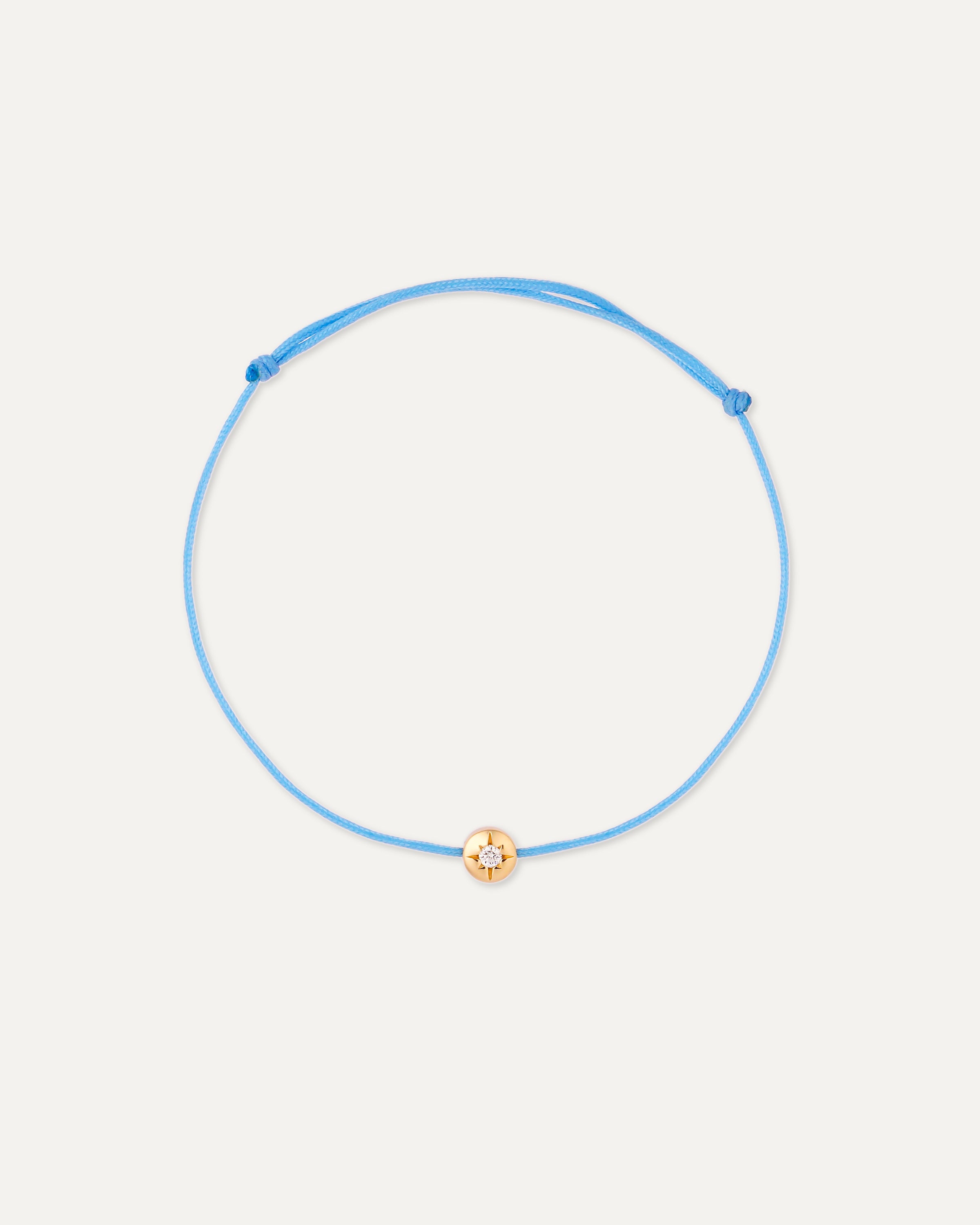 Blue bracelet with a diamond and solid gold charm on a white background