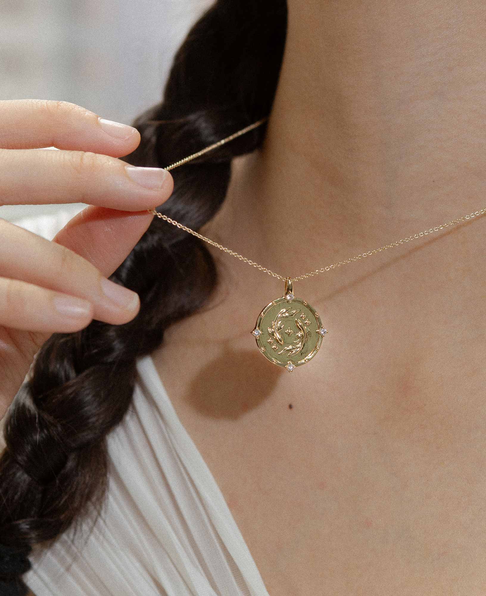 close-up shot of a model wearing the pisces horoscope gold pendant necklace≥