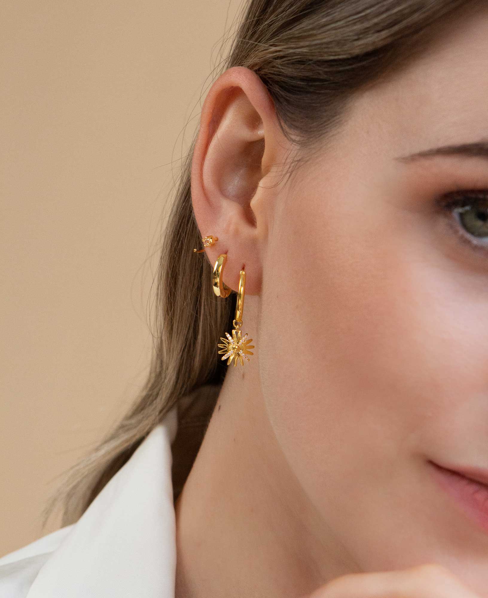 model wearing daisy flower 14k gold hoop earrings with earring stack